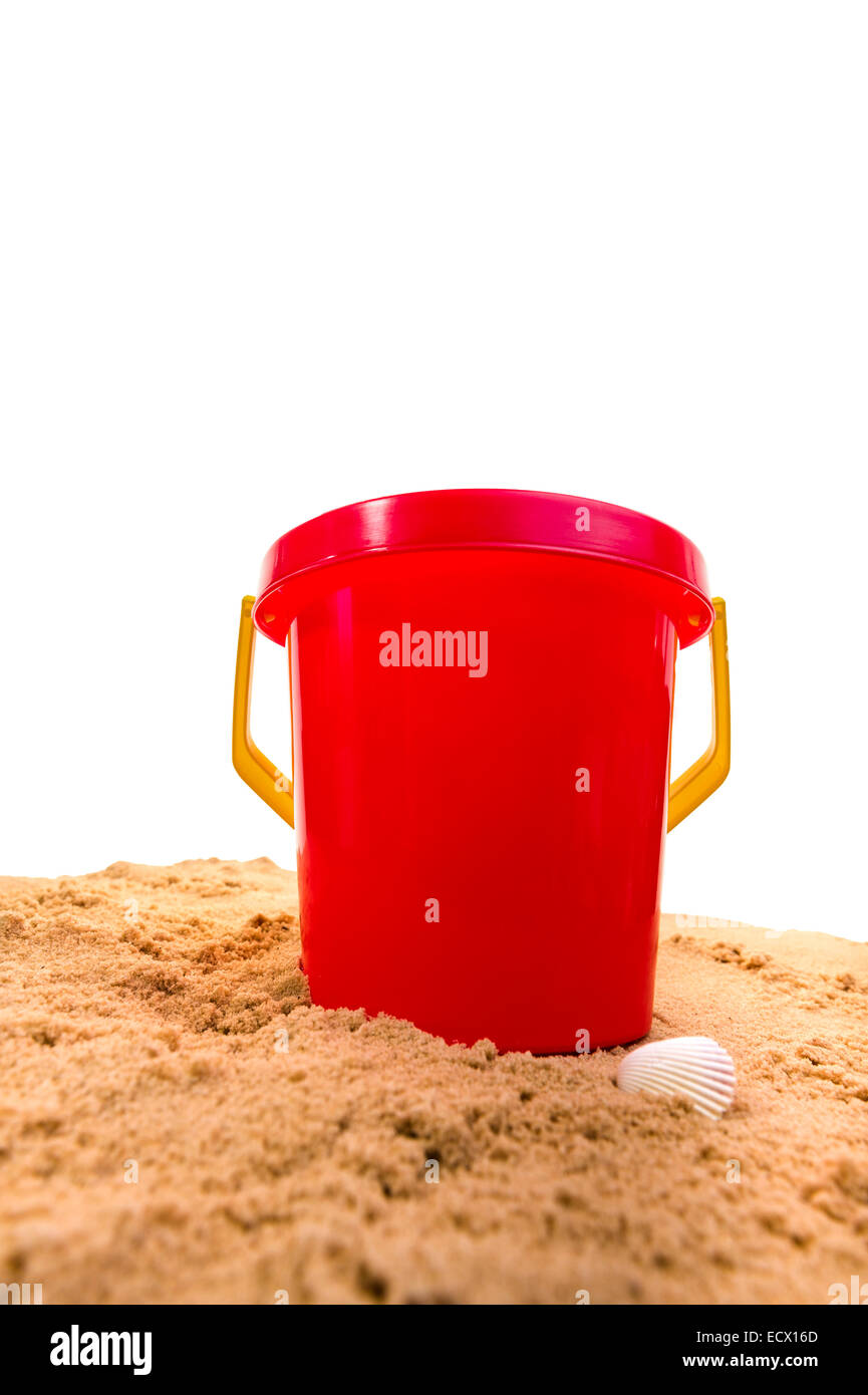 Red plastic bucket, sitting on sand. Stock Photo