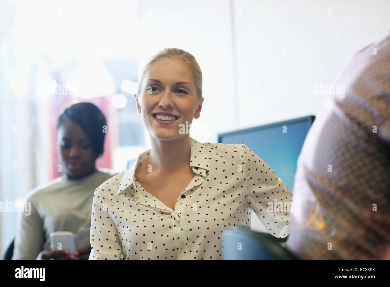 Smiling university student listening to seminar, young woman texting in background Stock Photo