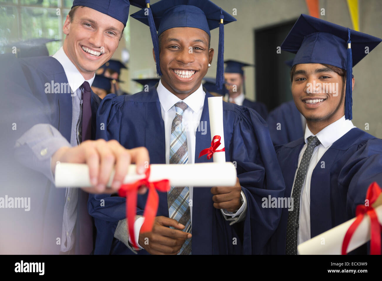 Portrait of smiling university students holding diplomas after graduation ceremony Stock Photo