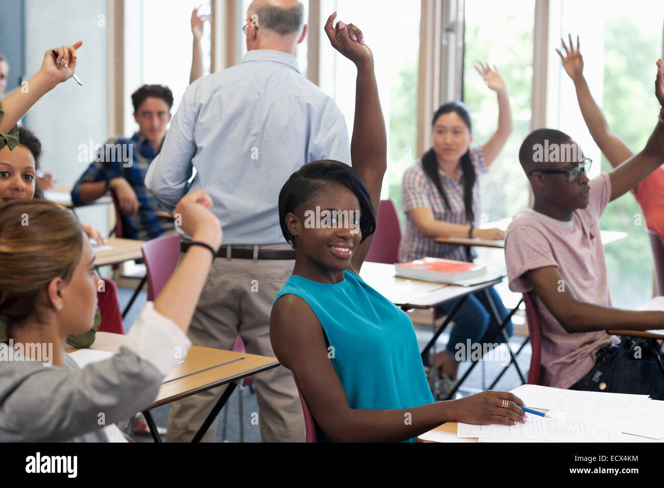 University students raising hands to answer professor Stock Photo