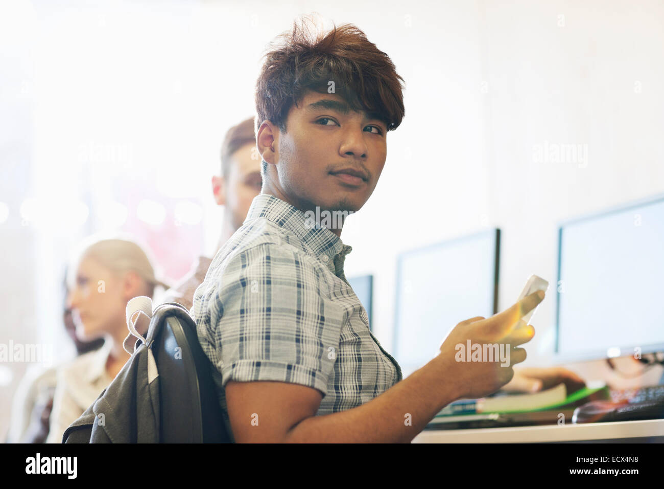 Male student sitting at desk using cell phone Stock Photo