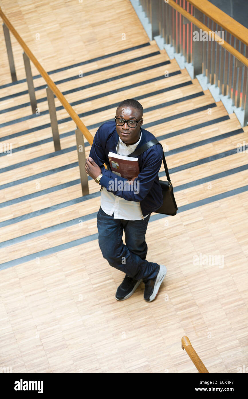 Male student holding books and standing in corridor Stock Photo - Alamy
