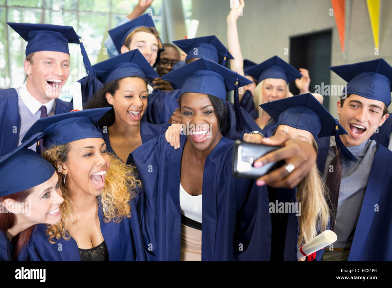 Group of smiling students in graduation gowns taking selfie on