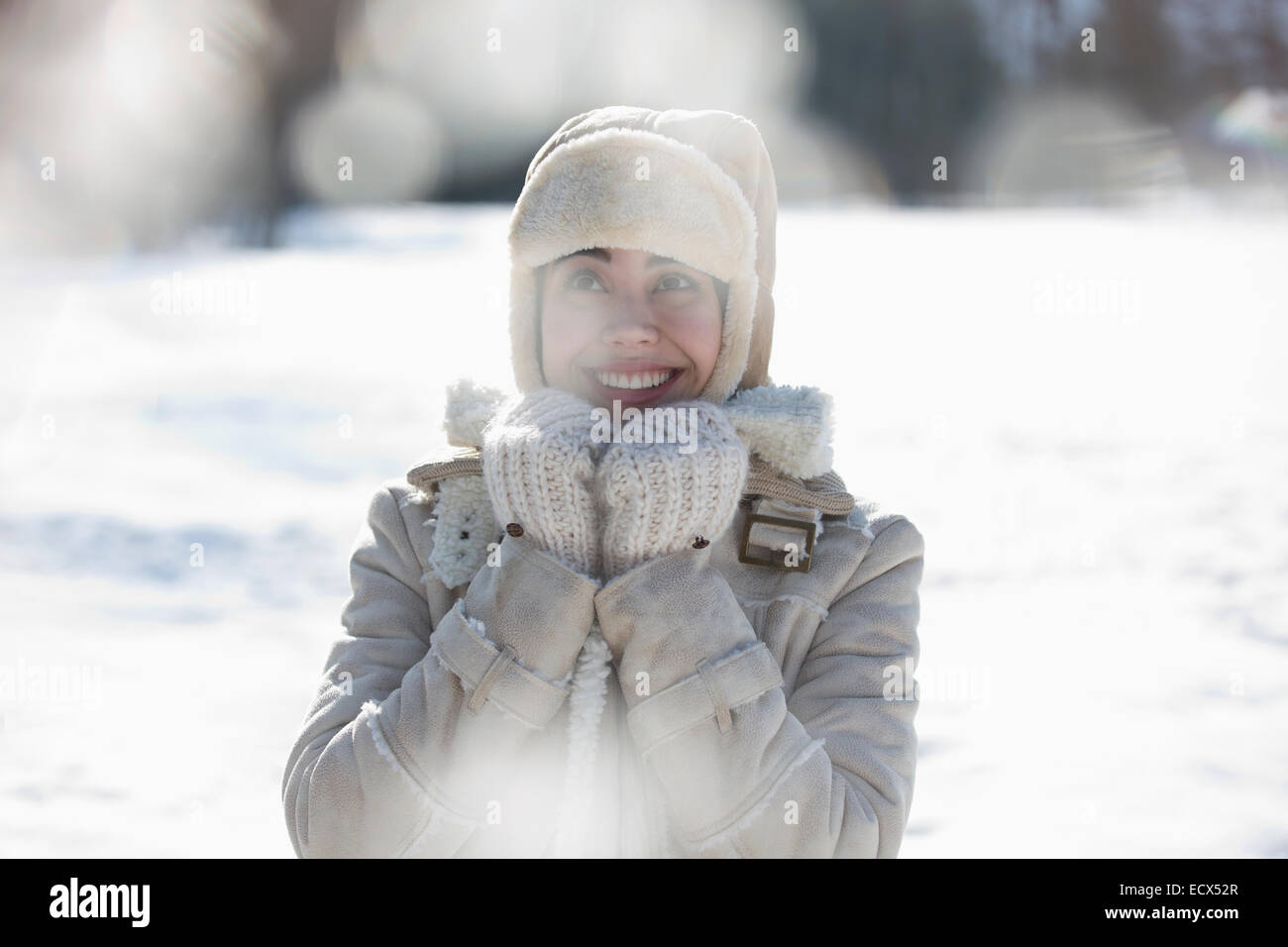 Woman in warm clothing smiling in snow Stock Photo