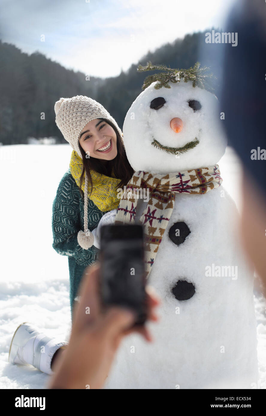 Man photographing woman with snowman Stock Photo