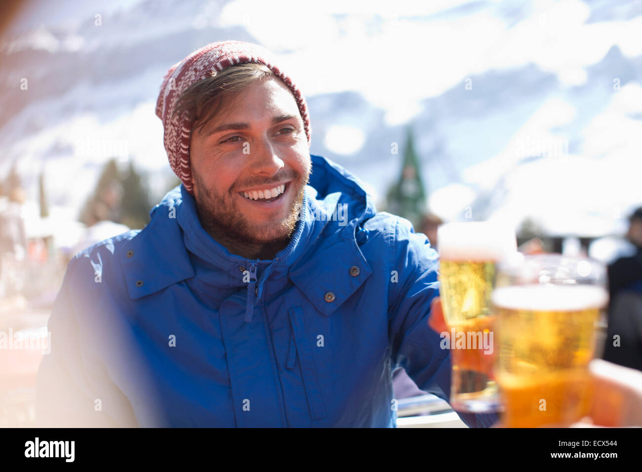 Smiling man in warm clothing drinking beer outdoors Stock Photo