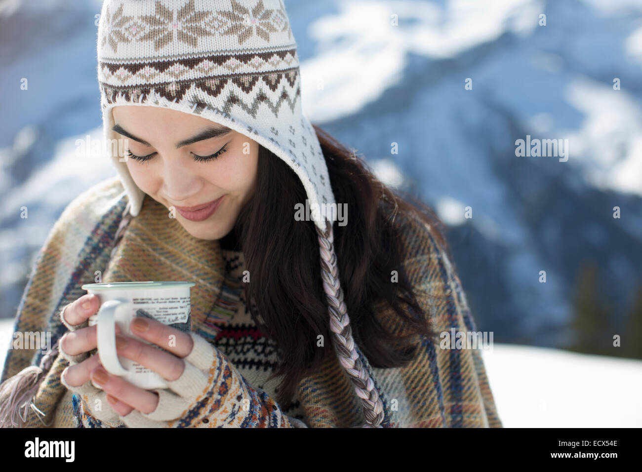 Smiling woman in knit hat drinking hot cocoa outdoors Stock Photo