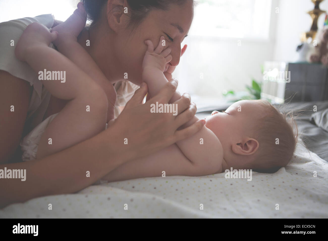 Mother playing with little baby, holding and kissing baby's hands Stock Photo