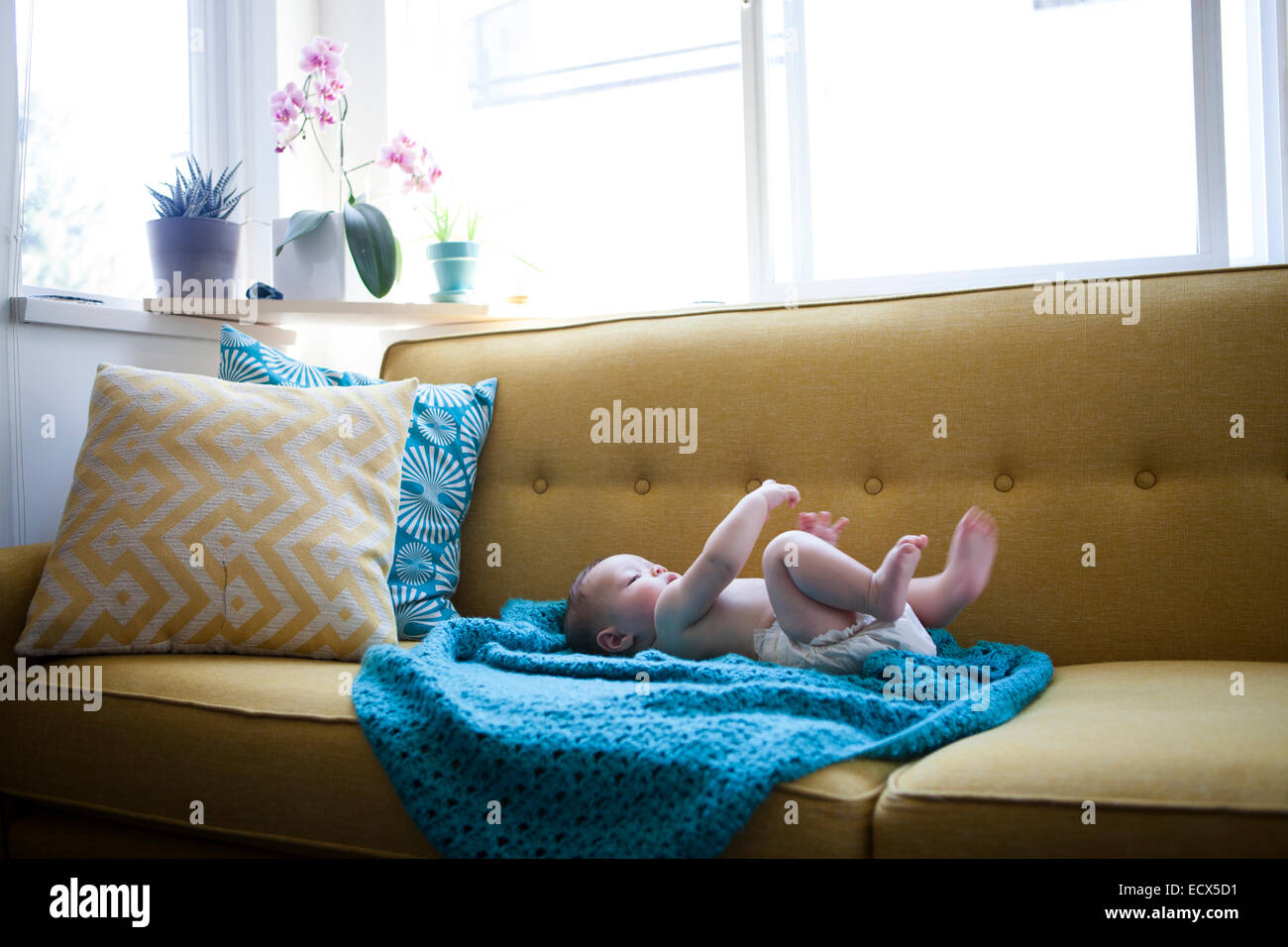 Little baby lying on blue cloth with arms and legs raised Stock Photo