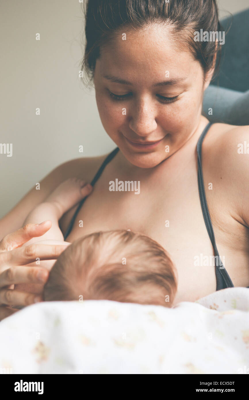 Portrait of mother smiling and breast-feeding little baby Stock Photo