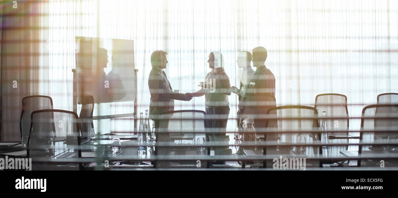 Business people standing in conference room shaking hands Stock Photo
