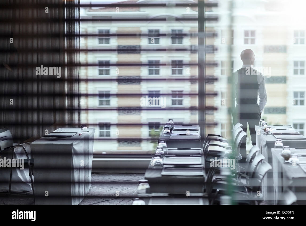 Young businessman standing in conference room looking out of window Stock Photo