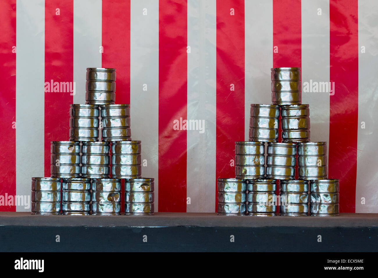 Two pyramids of tin cans for throwing balls at them on red white striped background Stock Photo