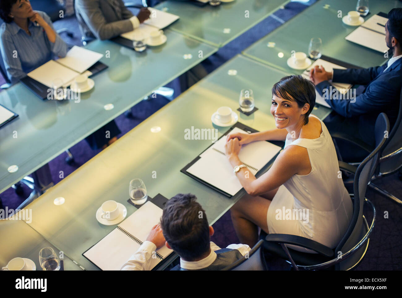 High angle view of smiling businesswoman looking at camera and sitting in conference room Stock Photo