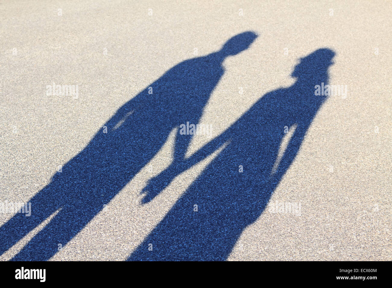 Two lovers cast a long shadow while holdings hands Stock Photo