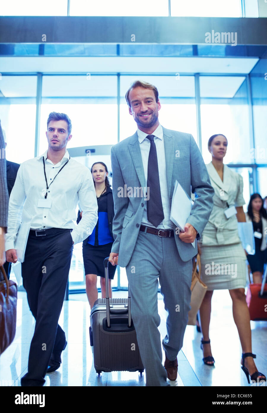 Businessman with suitcase and documents walking in office Stock Photo