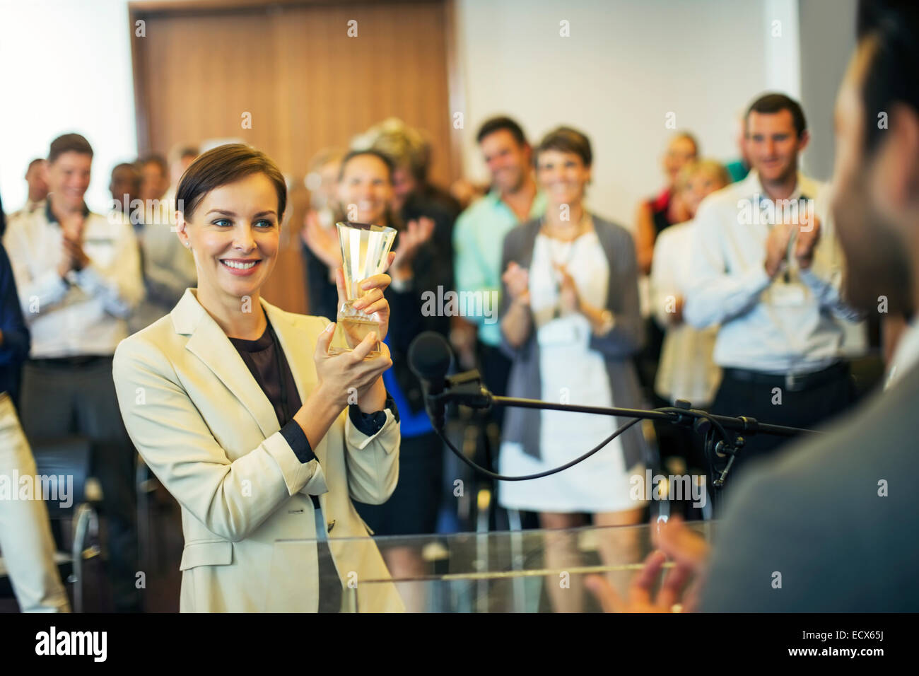 Businesswoman giving award to businessman, colleagues in background Stock Photo