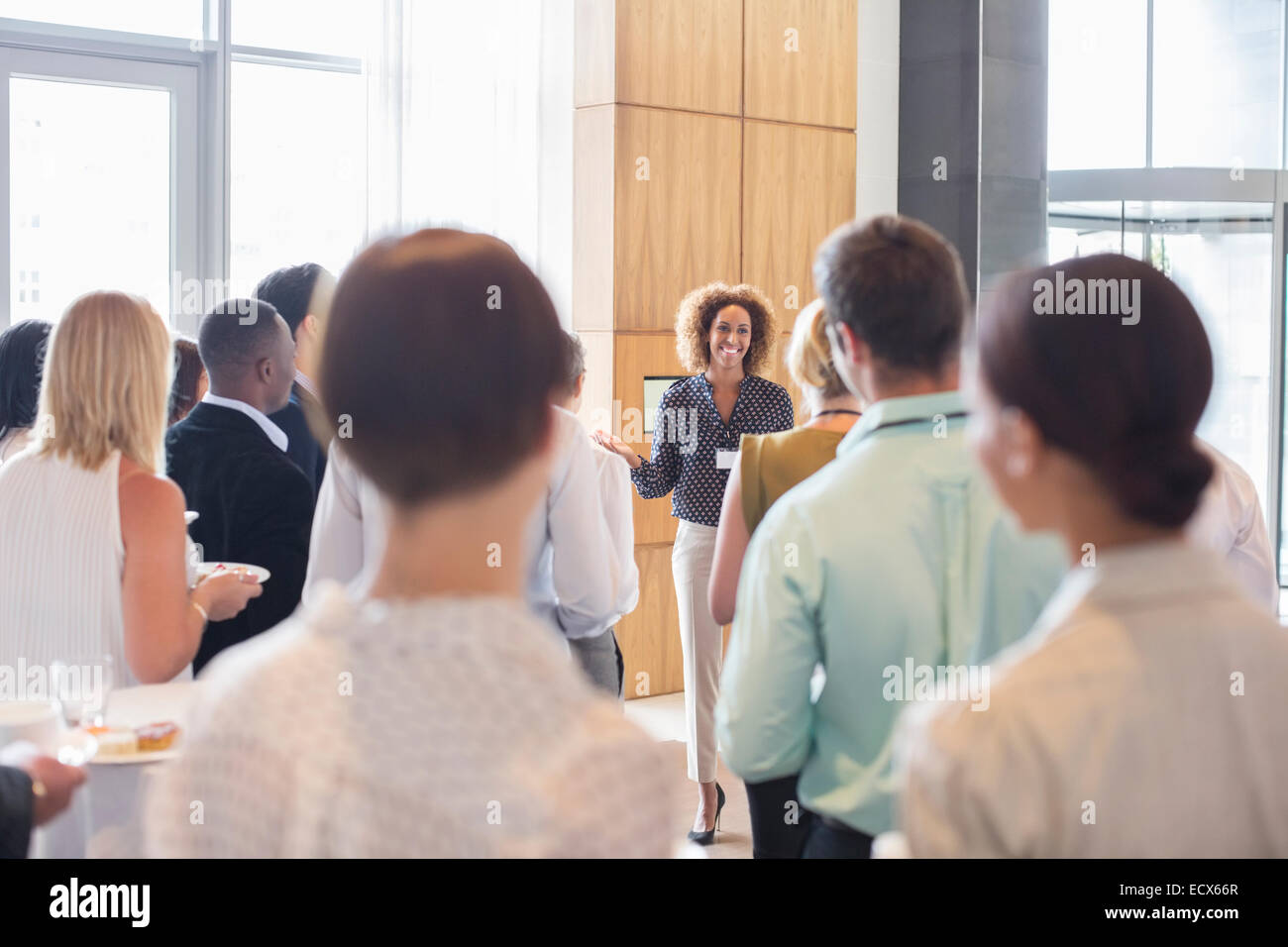 Business people standing in office hall holding trays with cakes and drinking water Stock Photo