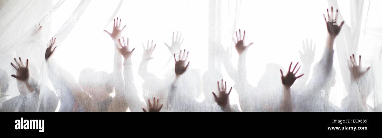 Silhouette of people raising hands behind transparent curtain Stock Photo