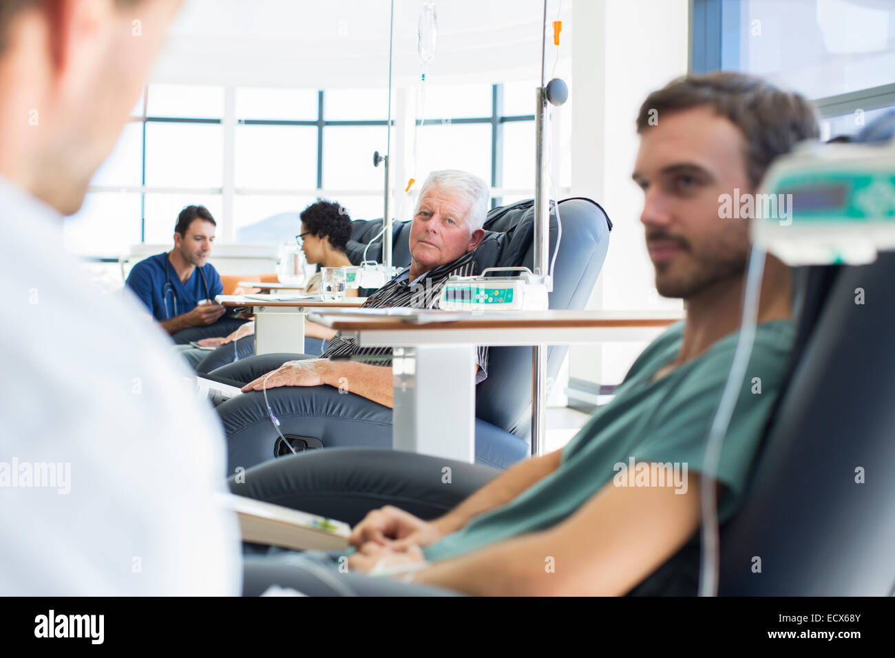 Doctors talking to patients receiving medical treatment in hospital