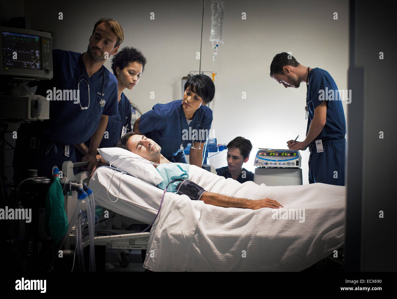 Group of doctors caring for patient in hospital ward Stock Photo