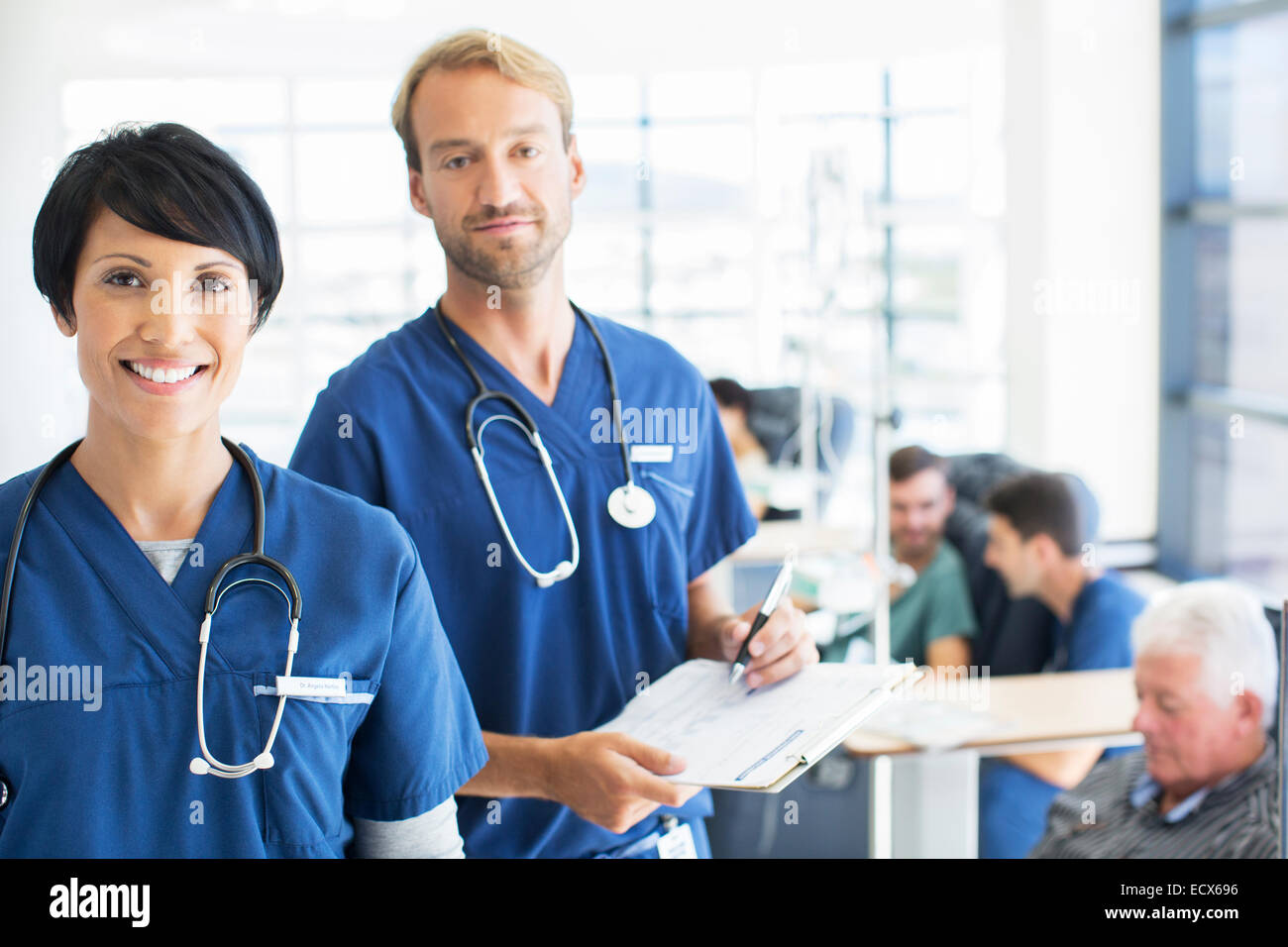 Portrait of doctors with patients receiving medical treatment in background Stock Photo