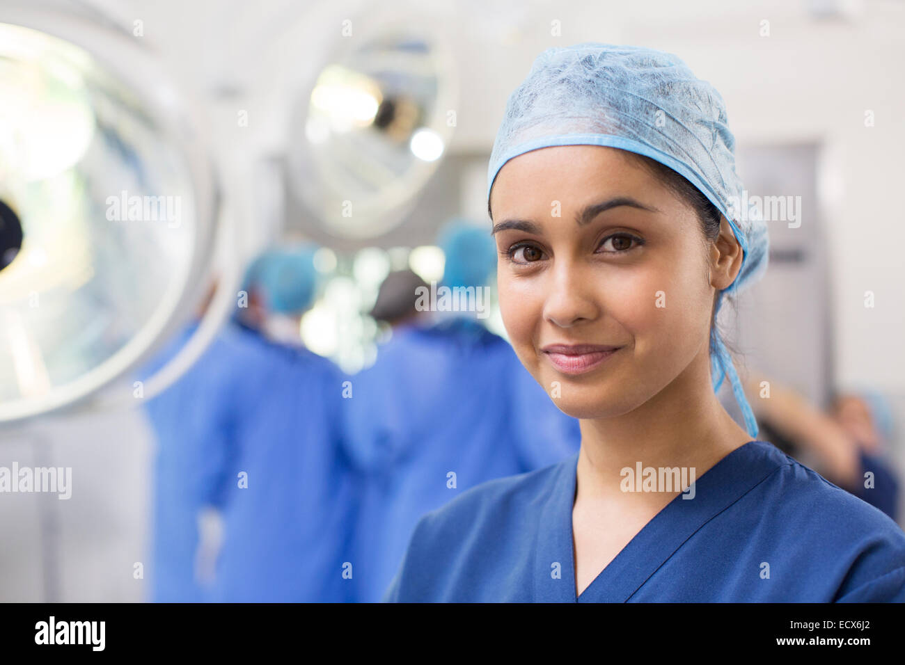 Portrait of smiling female surgical nurse wearing blue surgical cap and scrubs Stock Photo