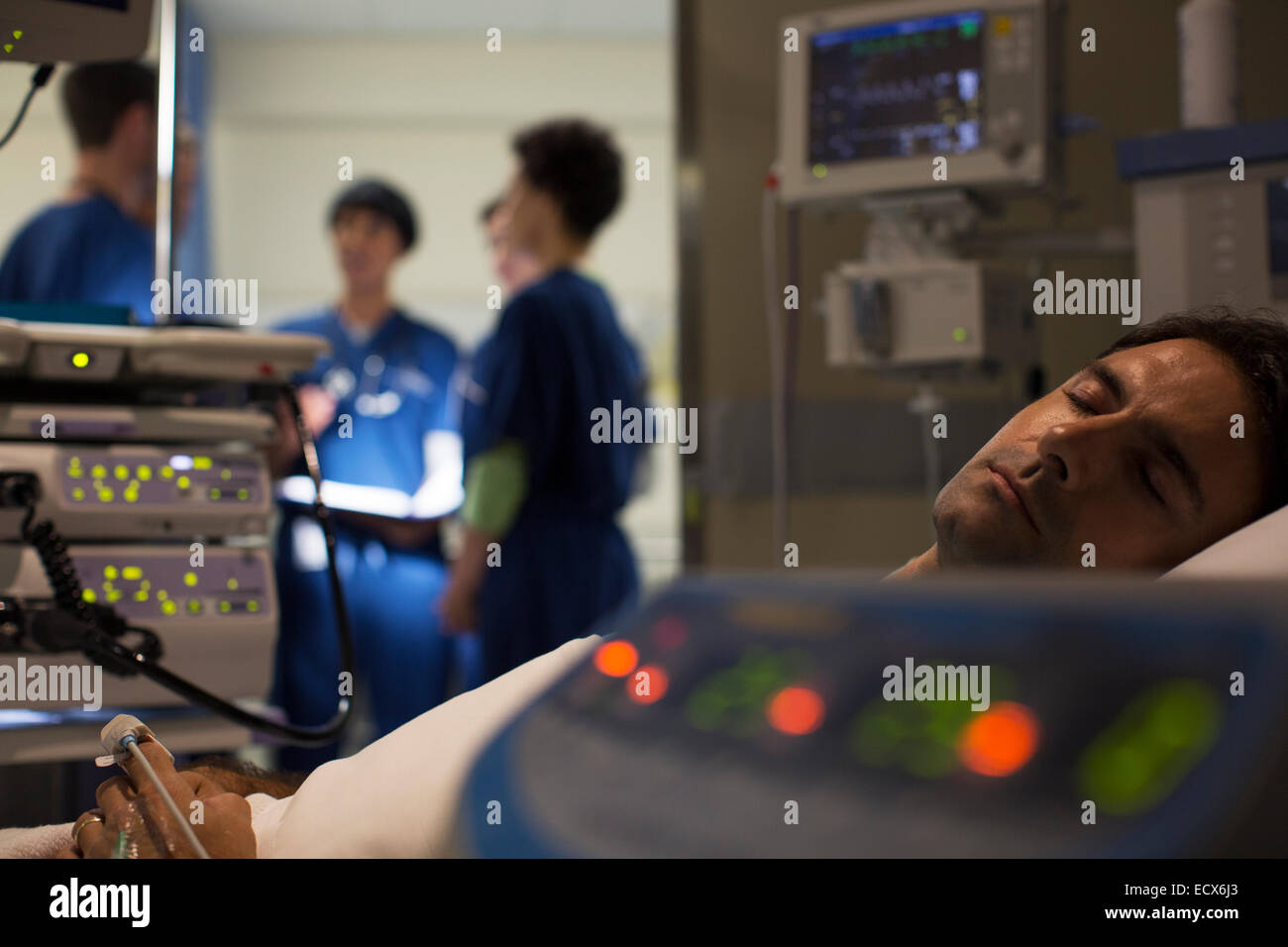 Patient surrounded by medical monitoring equipment in intensive care unit Stock Photo