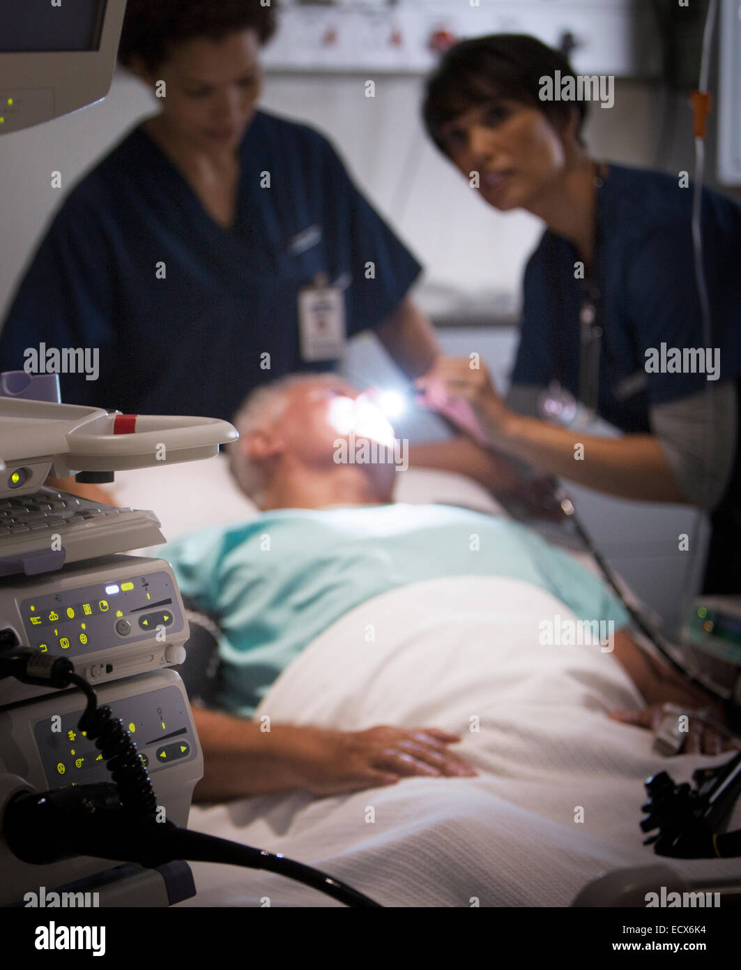 Doctor examining senior patient with flashlight in intensive care unit Stock Photo