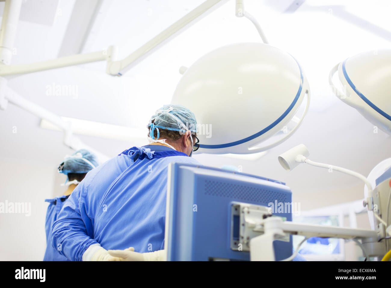 Rear view of doctor wearing surgical cap, mask and gown in operating theater Stock Photo