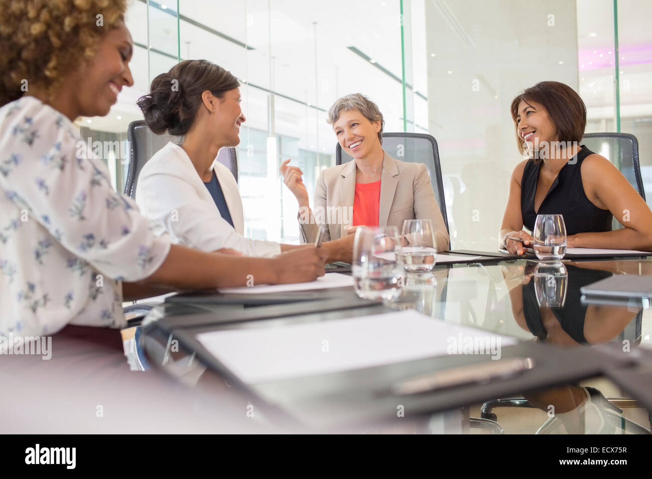 Businesswomen sitting at conference table talking Stock Photo