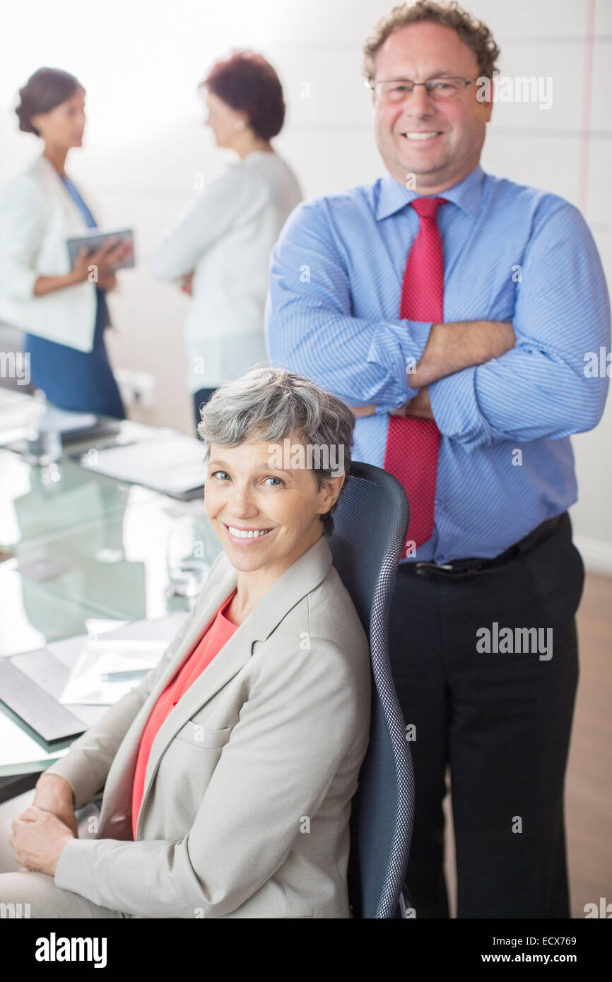 Two mature business people looking at camera, smiling in conference room Stock Photo