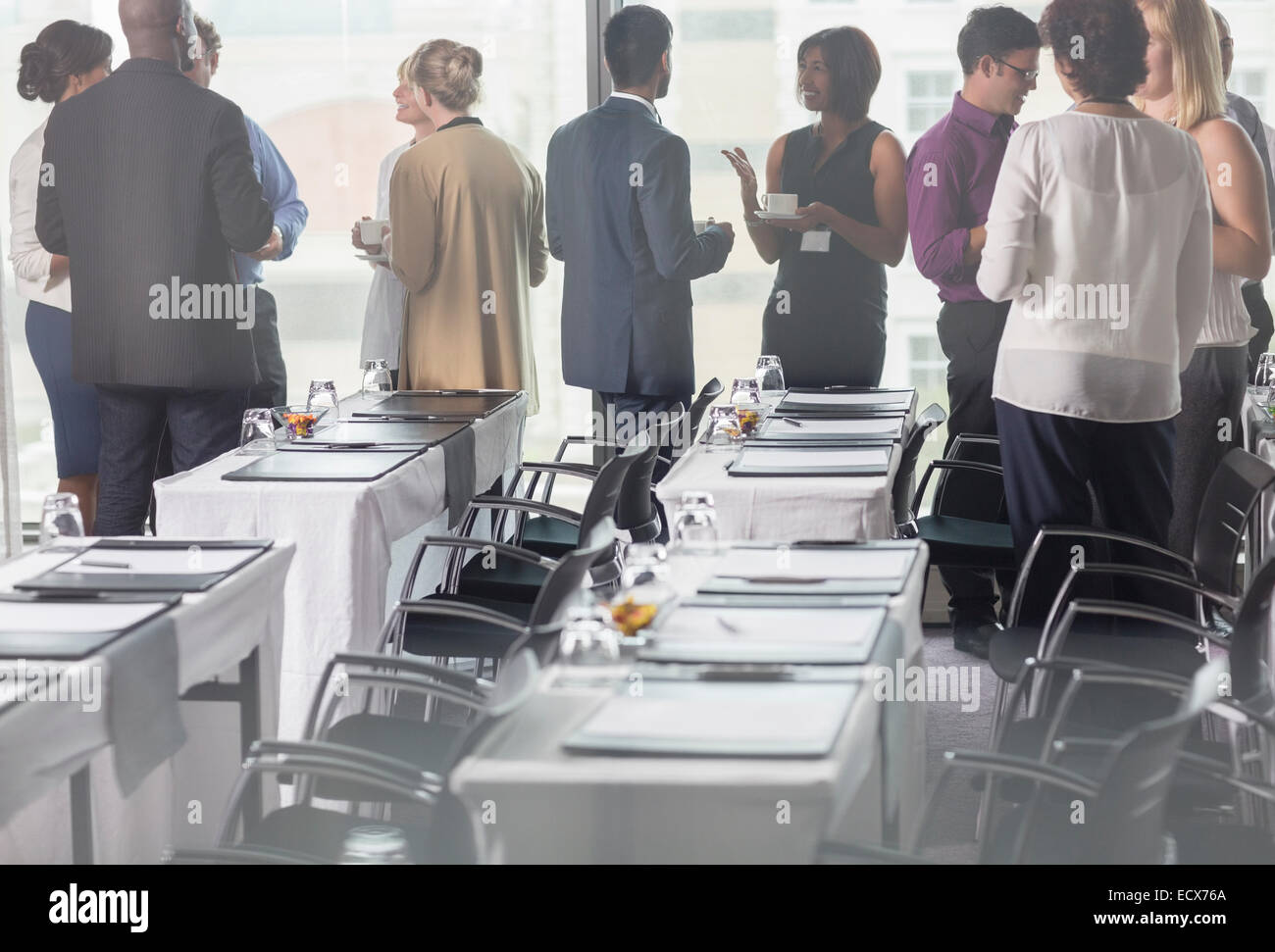 Business people holding coffee cups and discussing in conference room Stock Photo