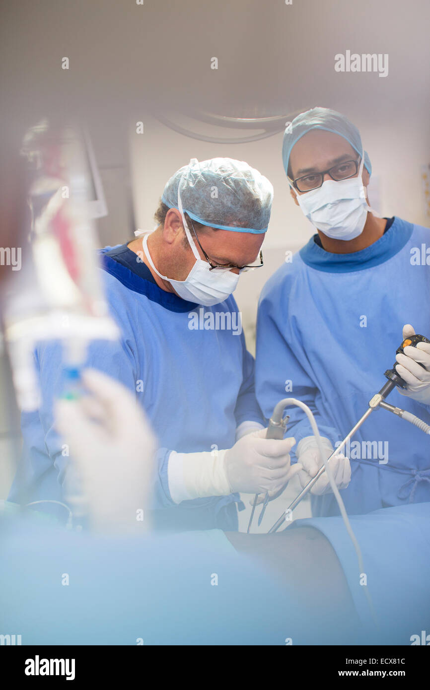 Mature doctors performing surgery and controlling liquid in saline bag Stock Photo