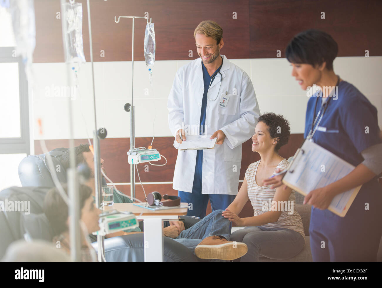 Doctors attending patients receiving intravenous infusion in hospital