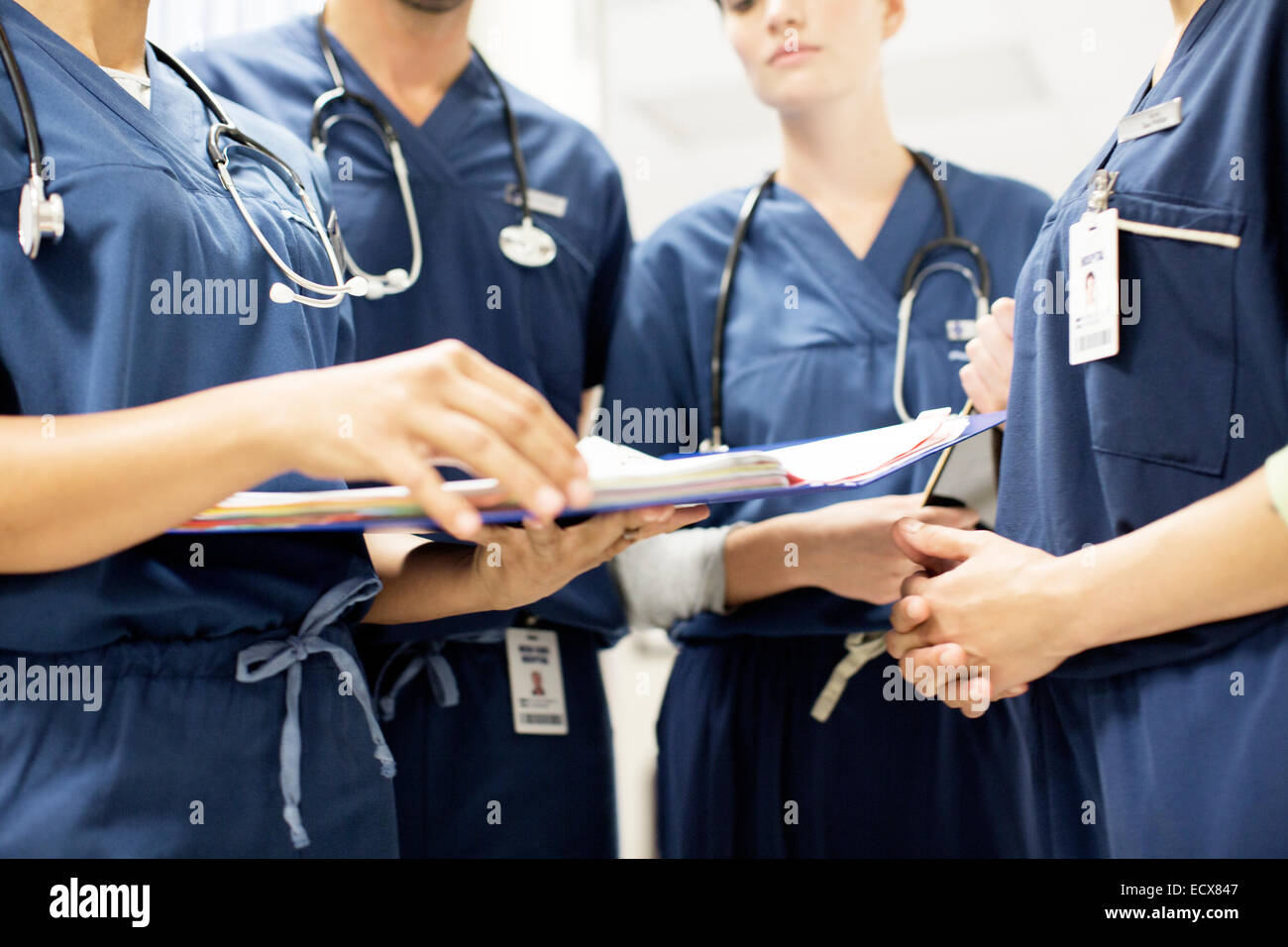 Team of doctors with stethoscopes looking at documents in hospital Stock Photo
