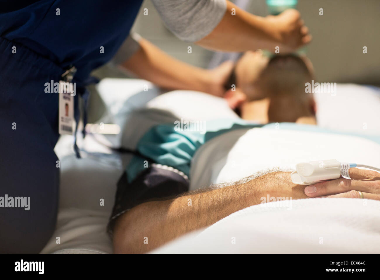 Doctor holding oxygen mask over male patient's mouth in intensive care unit Stock Photo