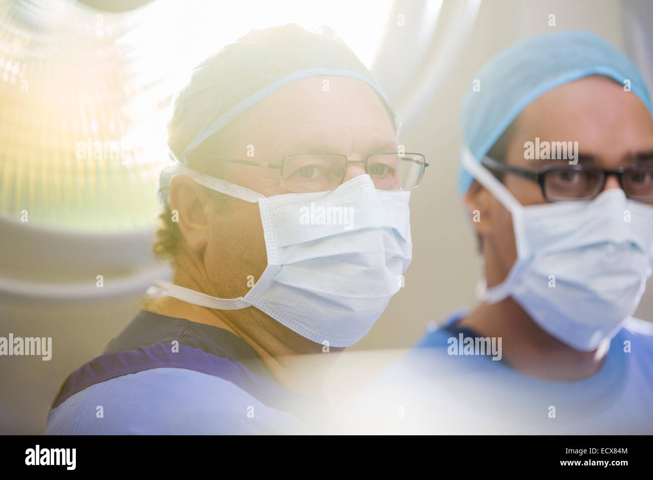 Portrait of two doctors wearing surgical caps, masks and glasses in
