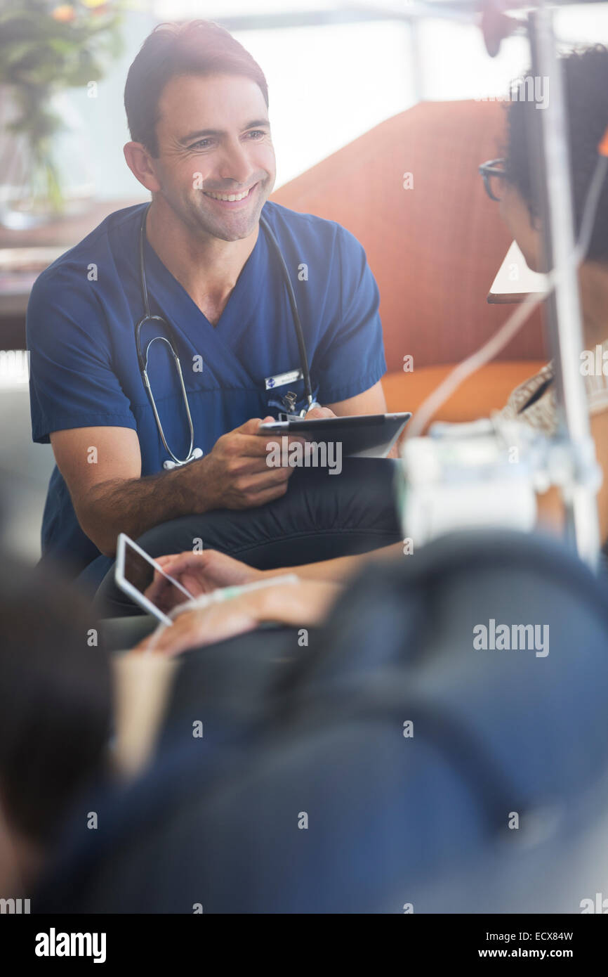 Doctor holding digital tablet, talking to patient undergoing medical treatment in outpatient clinic Stock Photo