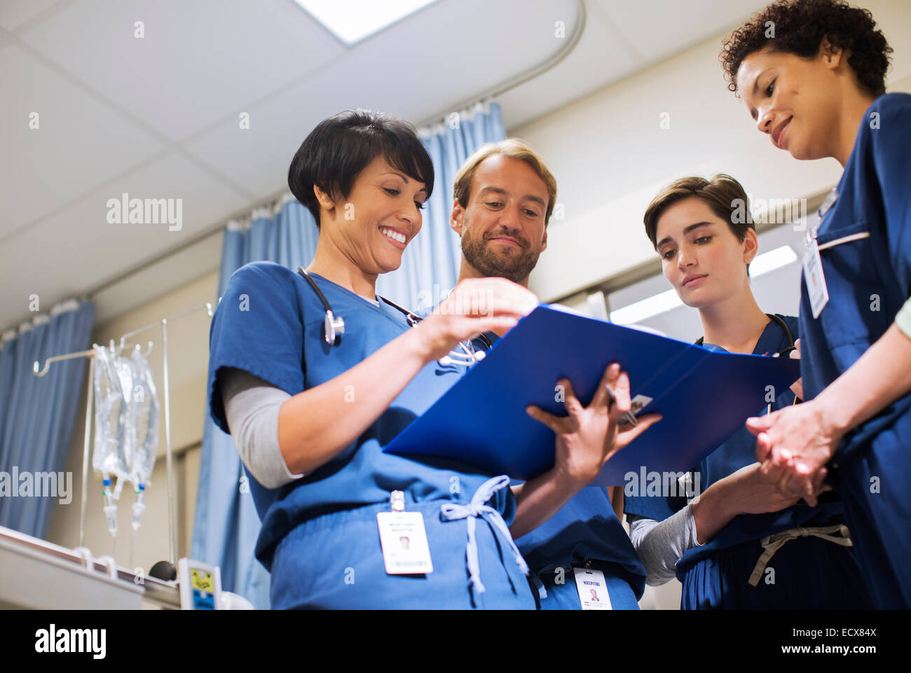 Doctors wearing scrubs, looking at documents in hospital ward Stock Photo