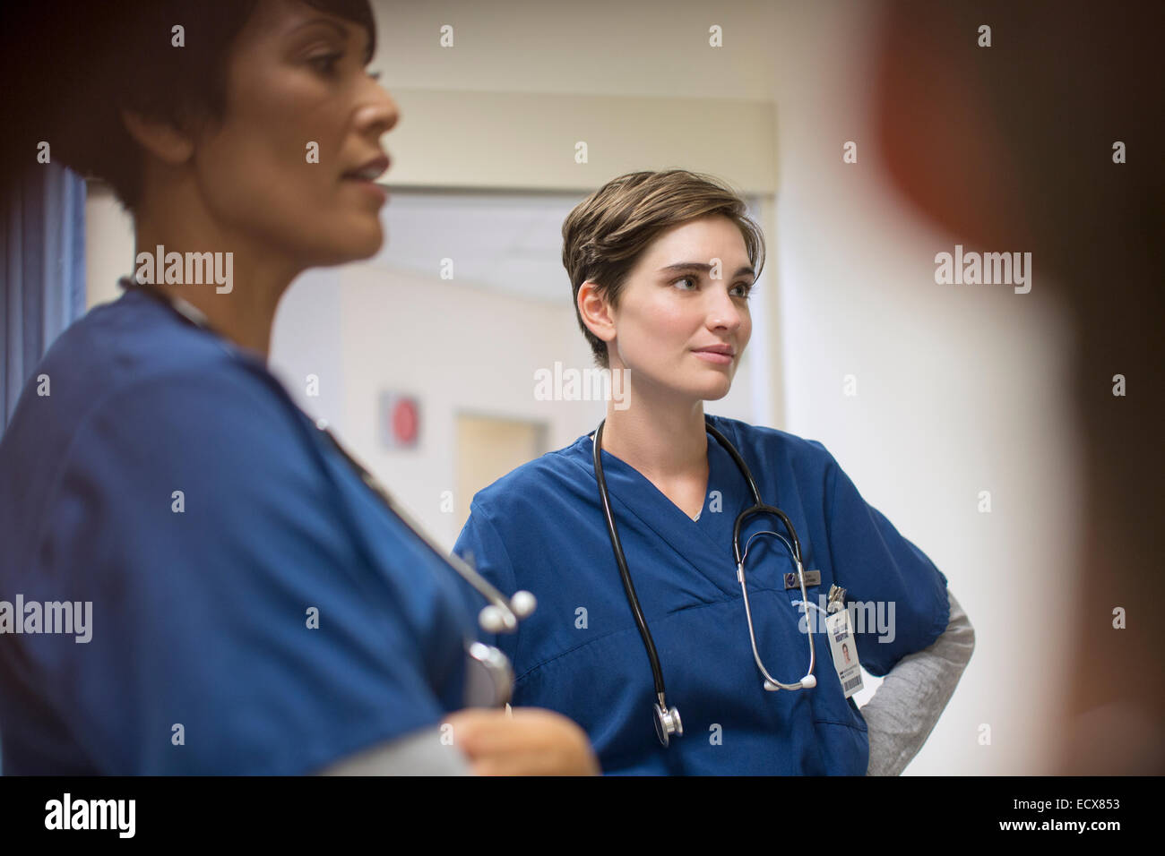 Two female doctors wearing navy blue scrubs, talking in hospital Stock Photo