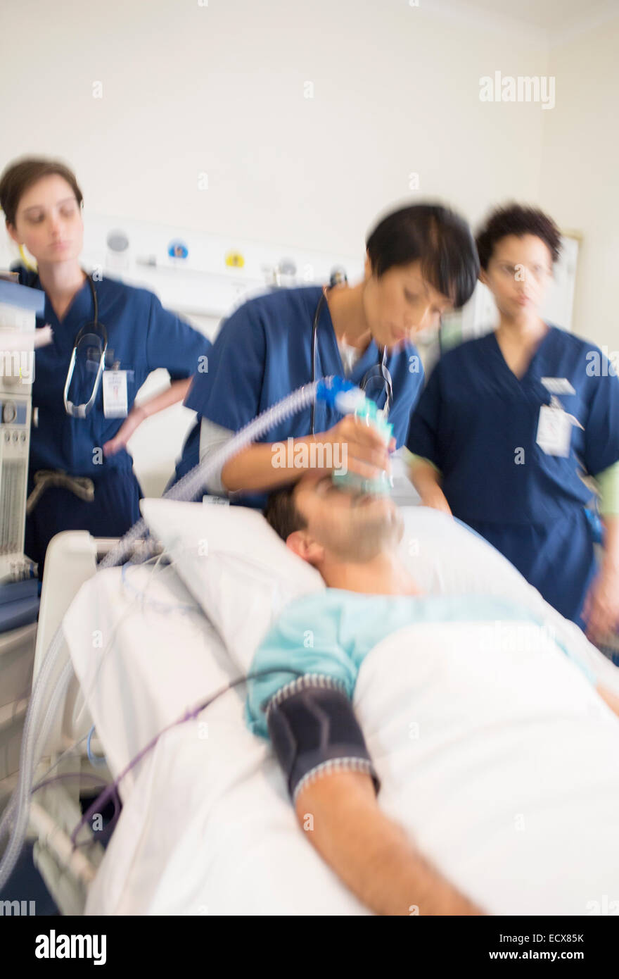 Team of doctors giving oxygen to patient in intensive care unit Stock