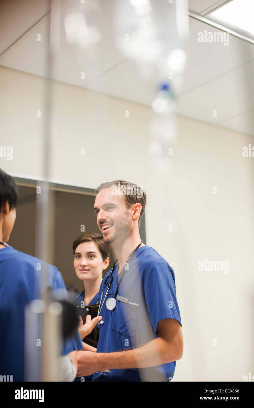 IV drip in front of doctors wearing scrubs talking in hospital Stock Photo