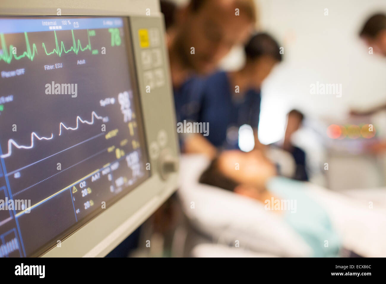 Heart rate monitor, patient and doctors in background in intensive care unit Stock Photo