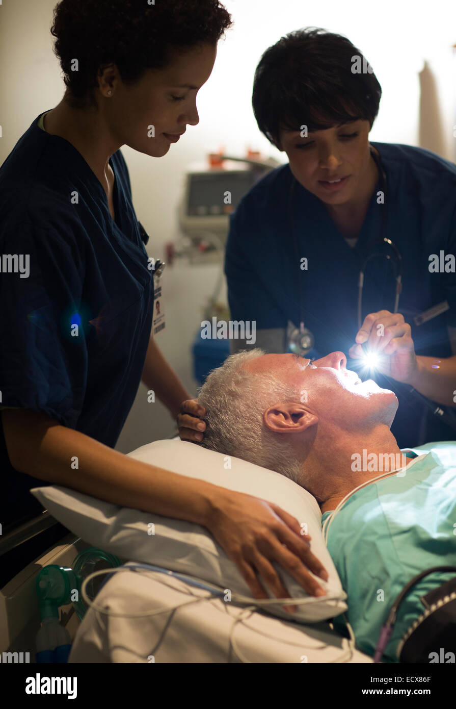Female doctor examining senior patient with flashlight in intensive care unit Stock Photo