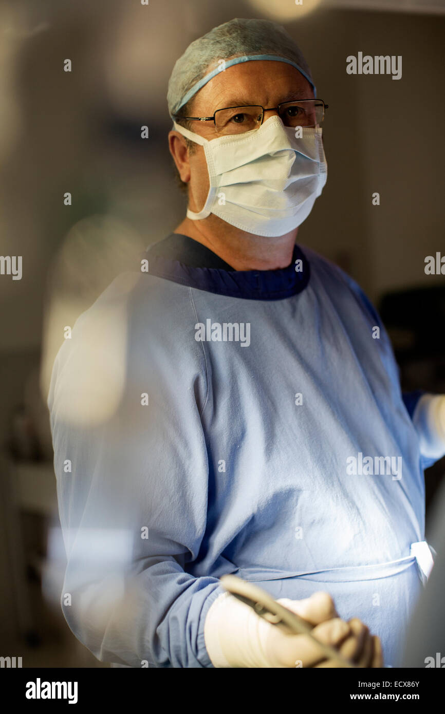 Surgeon wearing surgical mask, cap, gloves and gown in operating theater Stock Photo