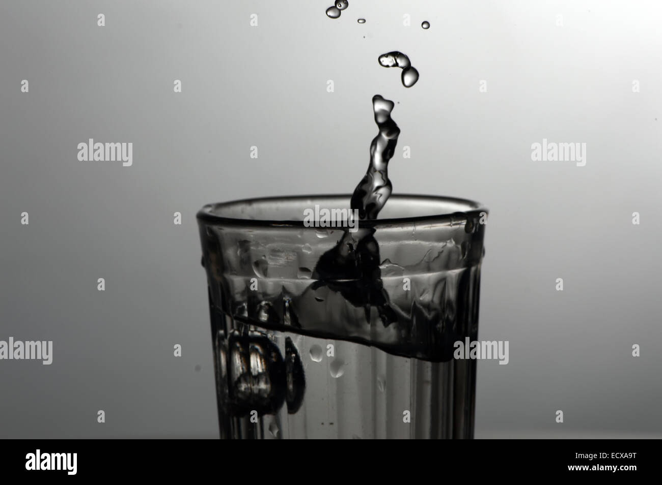 Splashes and drops of water in faceted glass Stock Photo