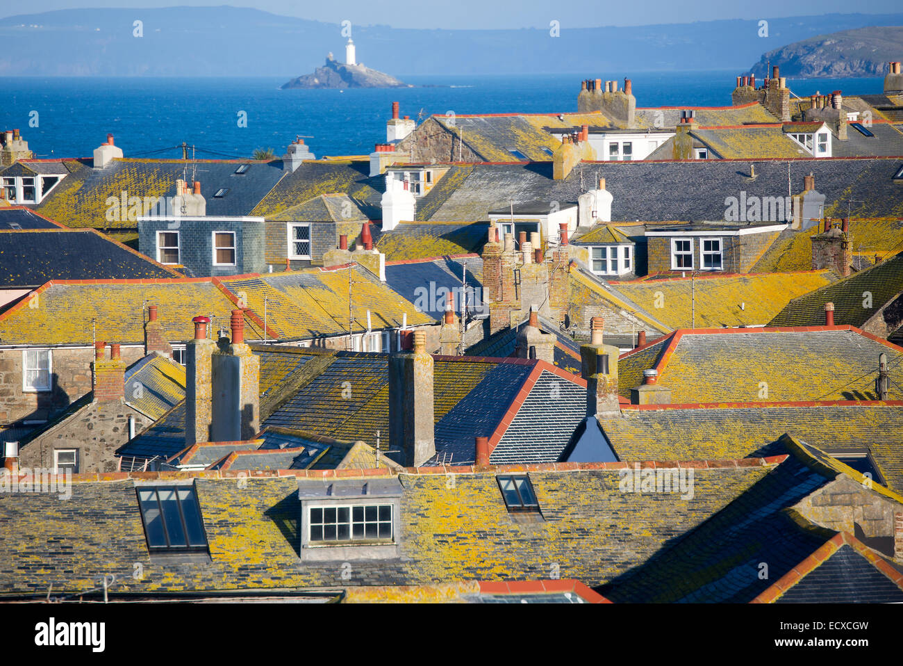 The lichen-covered roofs of St. Ives with Godrevy lighthouse beyond, Cornwall, England, UK. Stock Photo