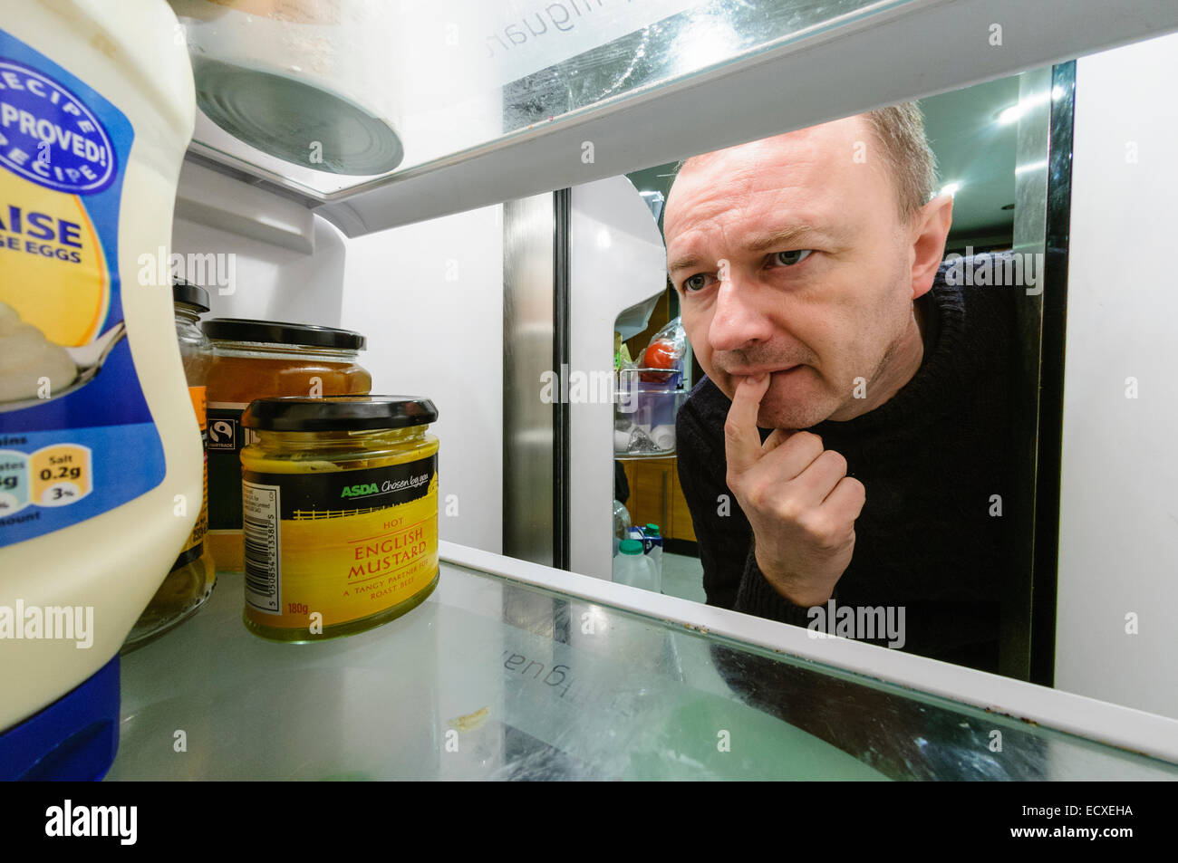 Man looks in a refrigerator with a puzzled look on his face. Stock Photo