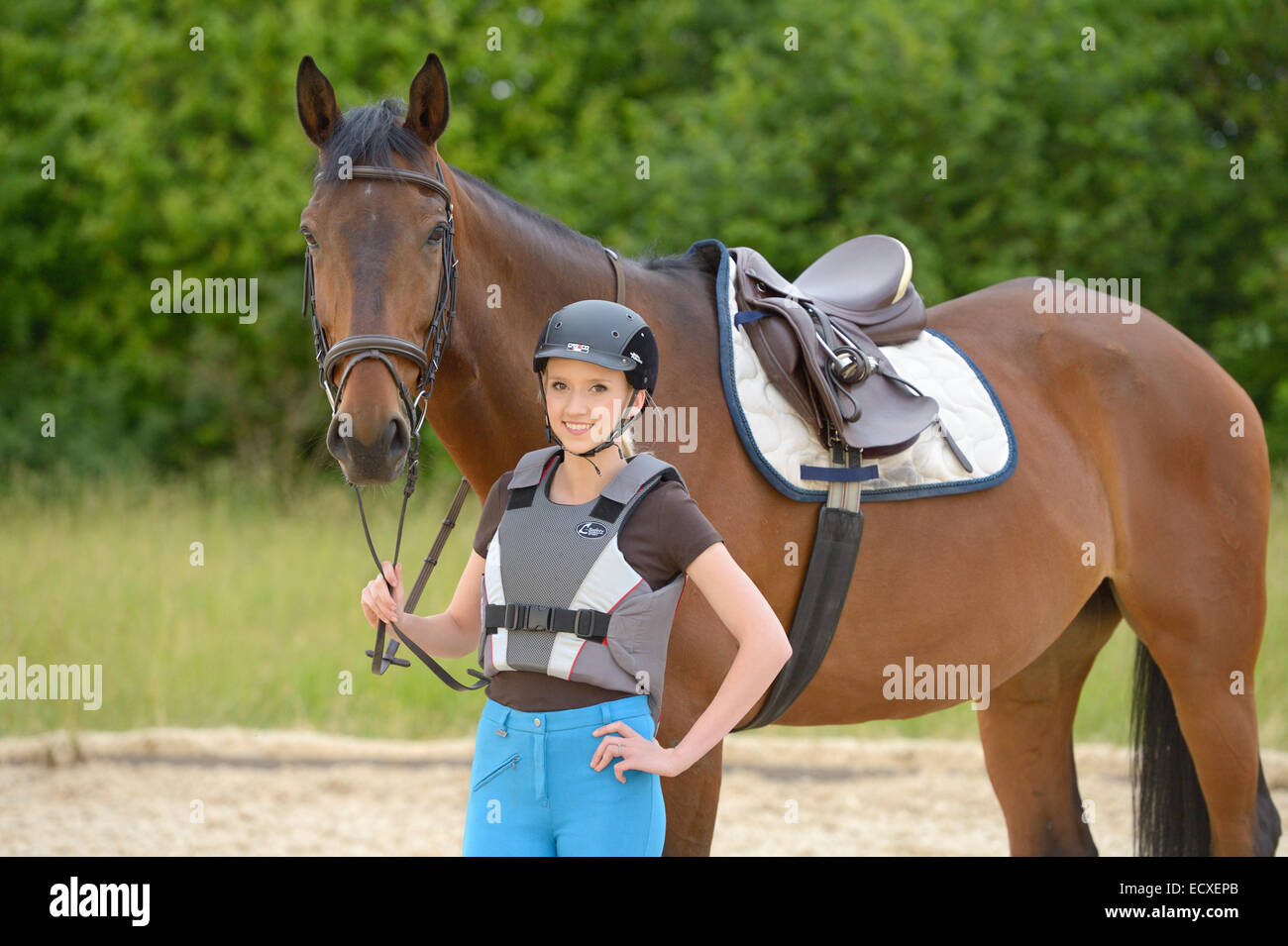 Young rider wearing a riding helmet and a body protector and her Bavarian horse Stock Photo